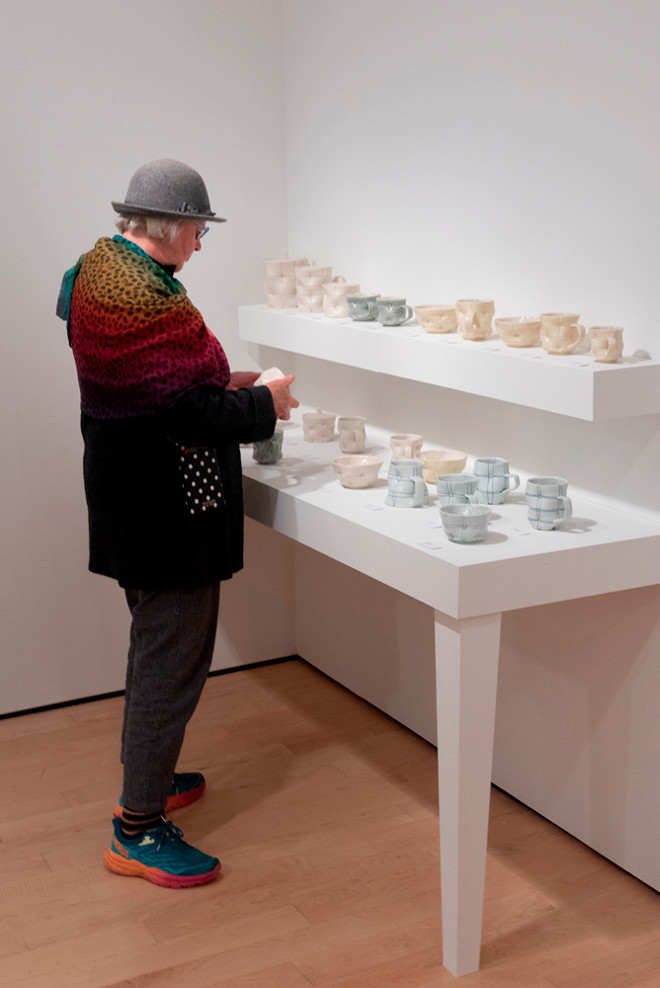 person viewing various pottery on a table