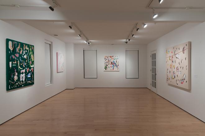 empty gallery space with various paintings and artwork hung on the walls