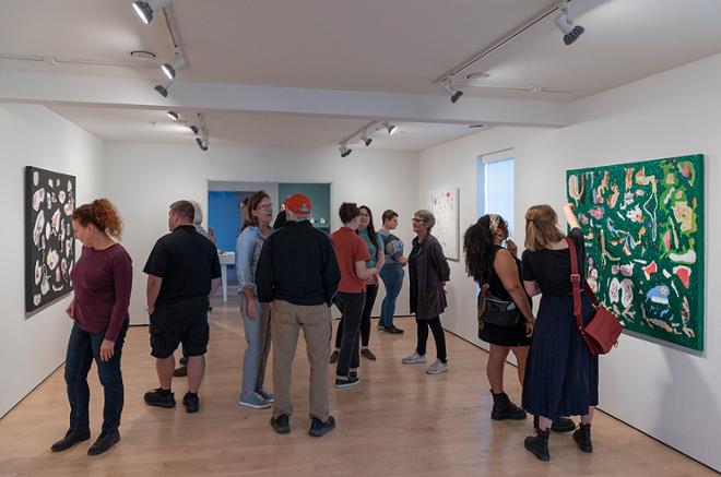 group of people viewing all the artwork on display