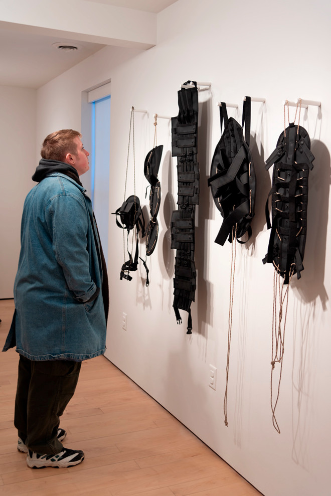 person looking closely at the harnesses hung on the wall