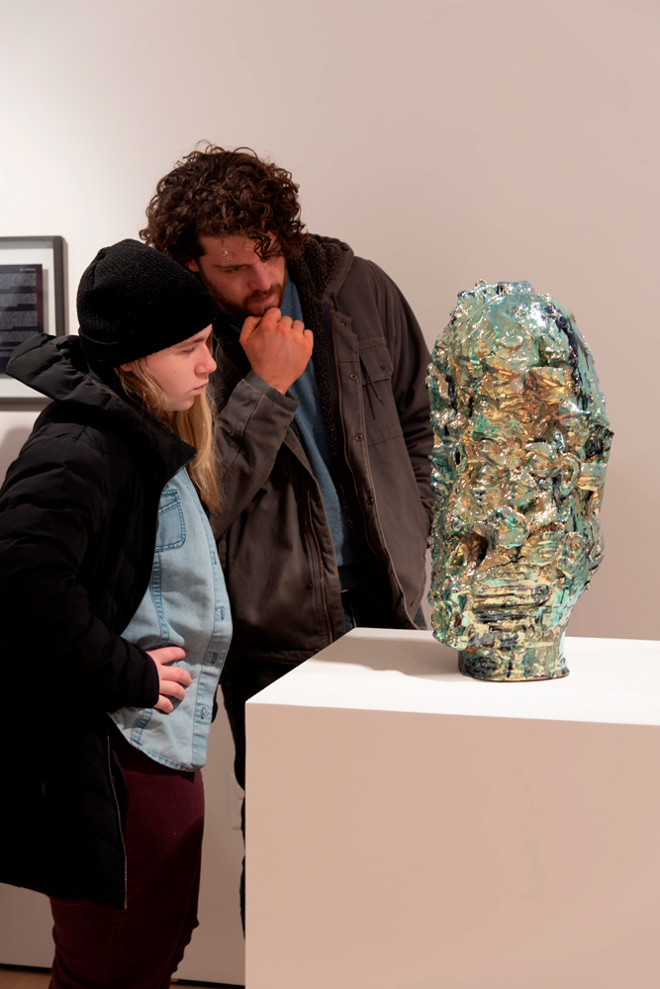 people looking on closely at a colorful glass sculpture