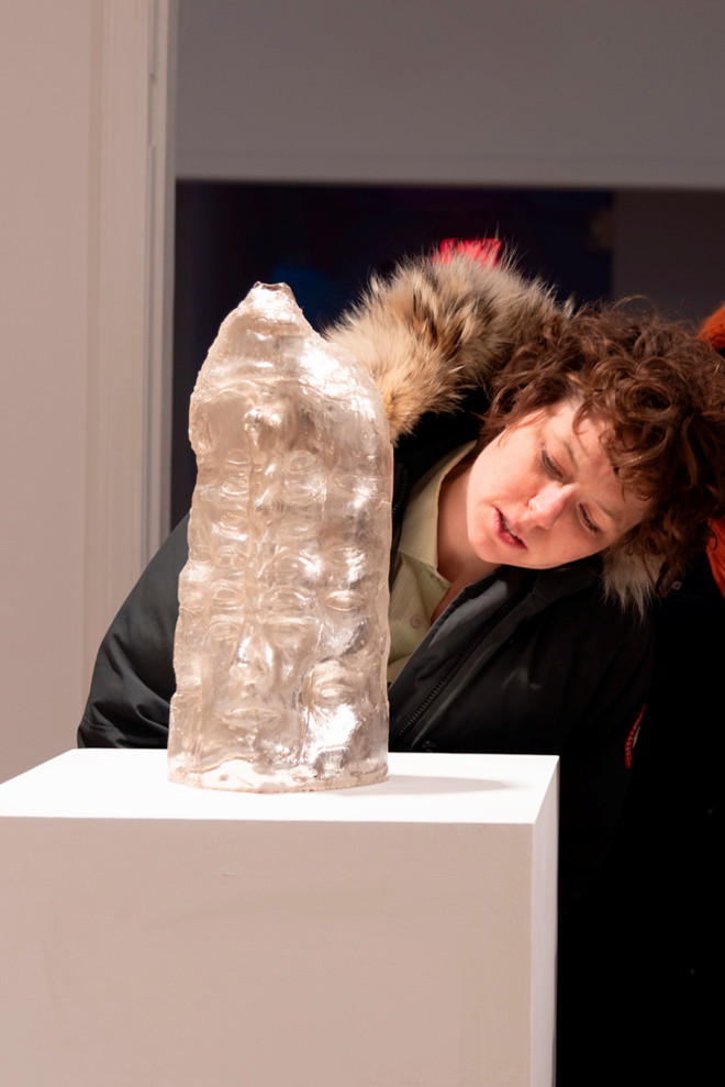 person looking closely at a sculpture