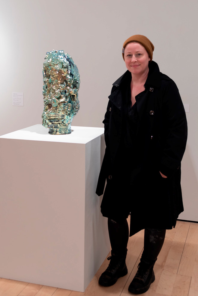 Artist posing next to their artwork