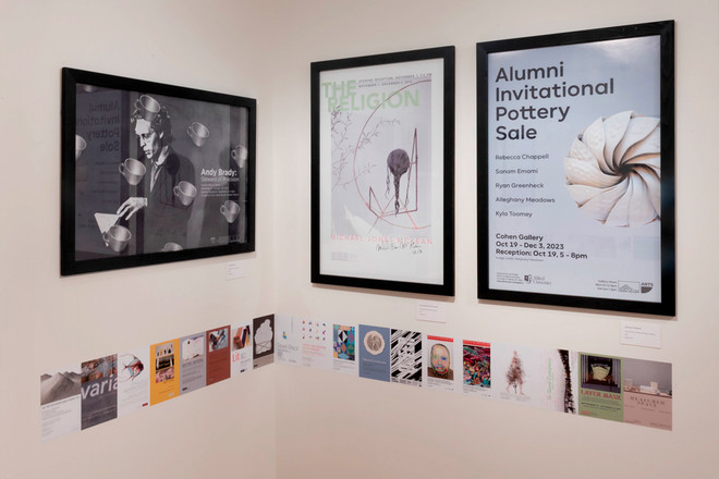A corner of the Cohen Gallery showcasing three framed posters: “Andy Brady,” “The Religion,” and “Alumni Invitational Pottery Sale.” Below the posters, a timeline of small exhibition cards is arranged horizontally along the wall.