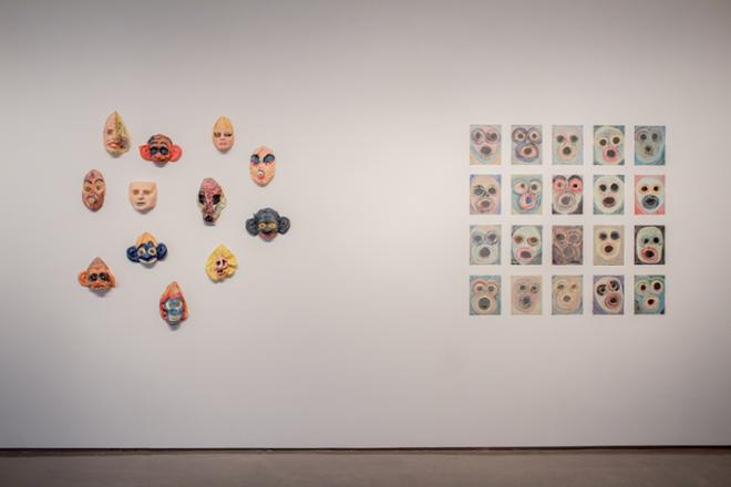 micheal mahalchick's artwork on a wall. One cluster of ceramic pieces and another grid of prints