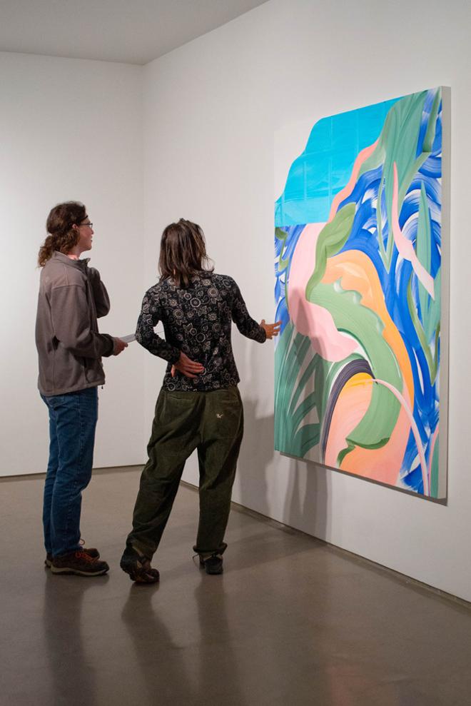 Two people viewing a large painting at the opening reception