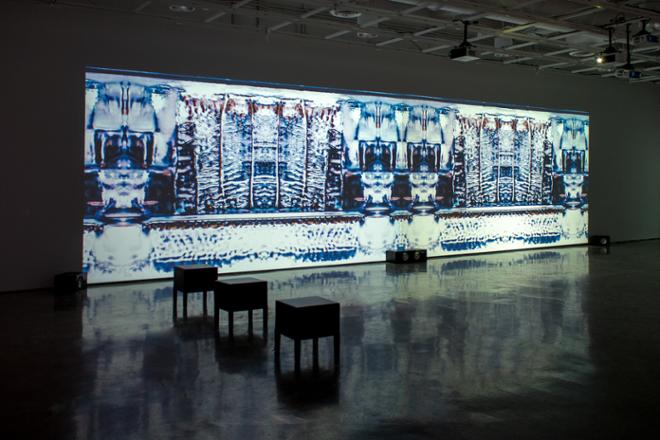 large projection on wall with seats on the gallery floor