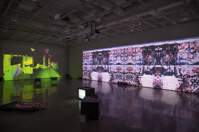 gallery filled with projections on the walls with monitors in the center floor