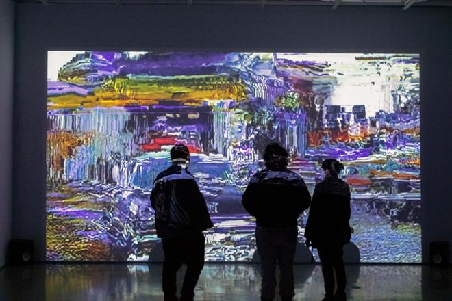 people observing video projection, a distorted multi-color still
