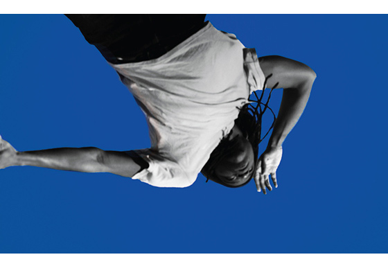 exhibit poster featuring an up shot of a person with one hand on their forehead looking out on a blue background