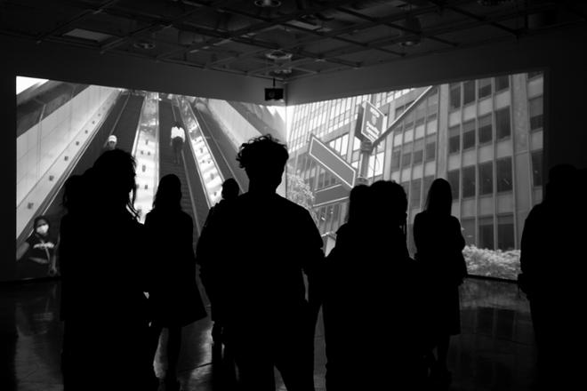 black and white toned image of people viewing video in the immersive gallery