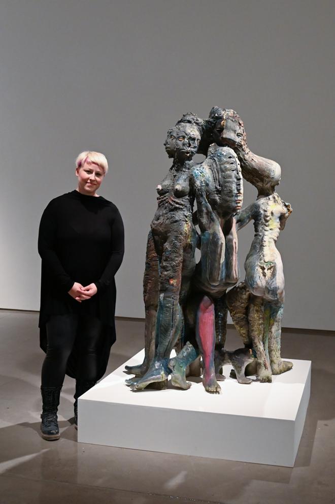 Stephanie Hanes posing with their abstract group of figures sculpture