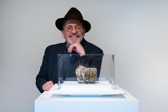 Wayne Highby posing with a sculpture in a glass case