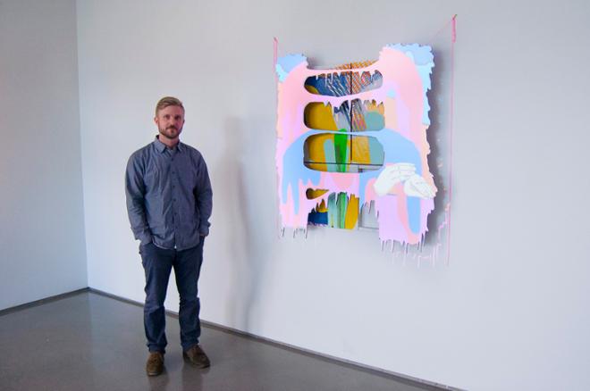 Derek Larson next to his artwork