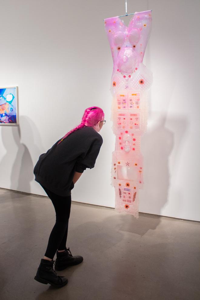 Guest viewing closely a tall sculpture that's iridescent pink