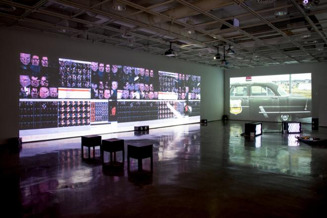 empty gallery space with video projections playing on the gallery walls