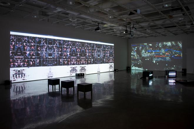 empty gallery space with video projections playing on the walls