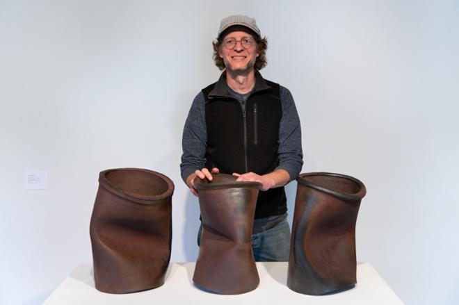 Matt Kelleher posing with bronze dented cans sculpture