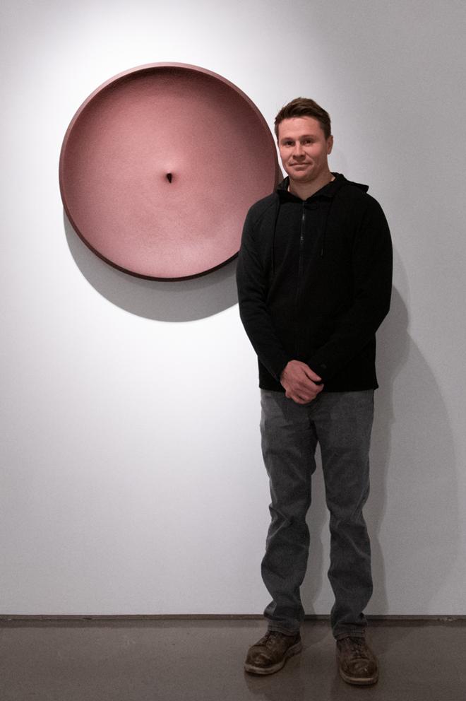 Shawn Murrey posing with their large bronze plate piece