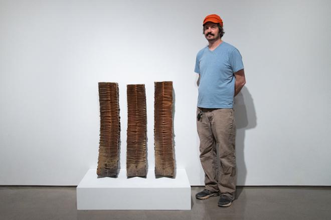 James Tingey posing with three curved column pieces leaning against the wall