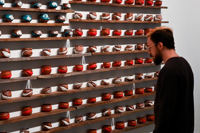 individual viewing art piece that depicts the flag of the United States with ceramic cups 