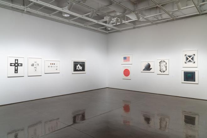 corner of gallery space filled with various prints