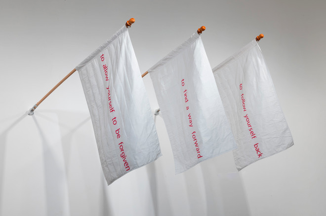 three white flags with various comforting messages