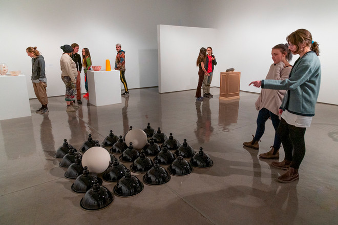 people looking at a sculpture on the floor