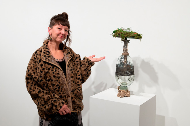 Artist posing next to their sculpture