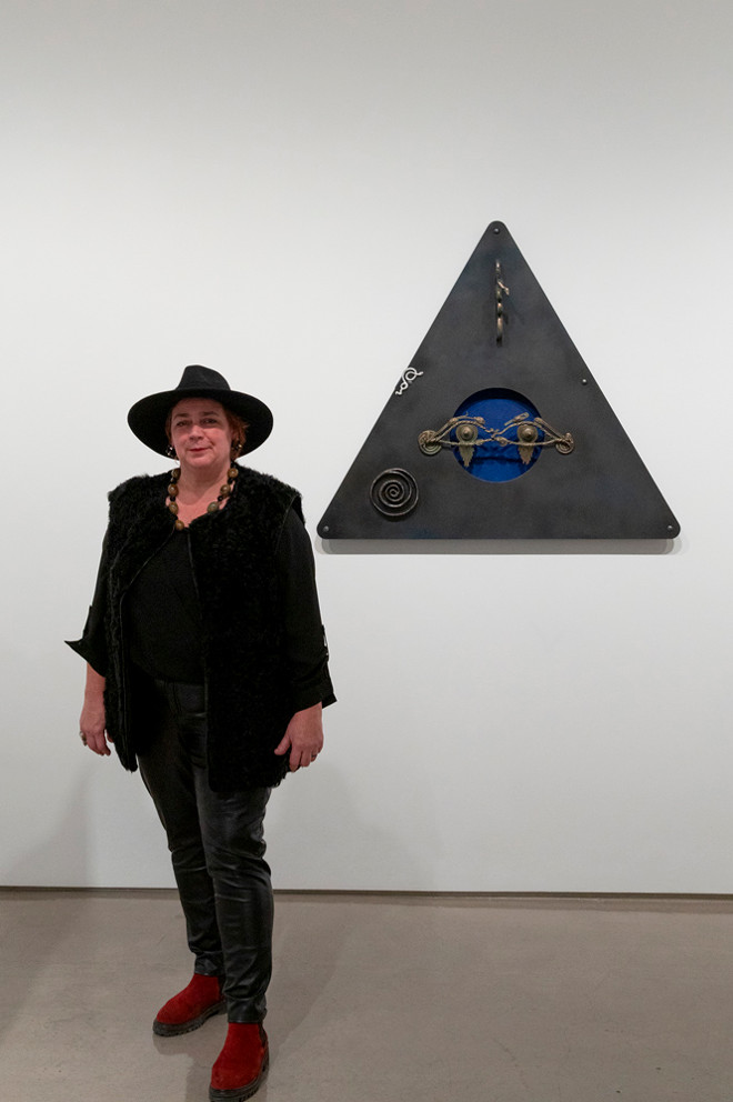 Artist Coral Lambert posing next to their artwork