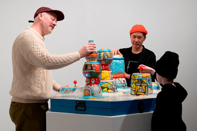 three people playing and interacting with colorful station of pots