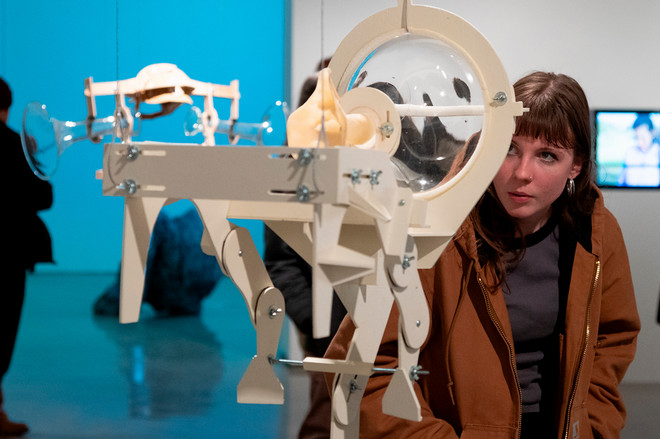 person looking closely at sculpture