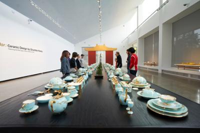 people viewing a table of artful dinnerware
