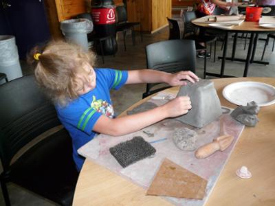 Young workshop attendee working on a clay piece