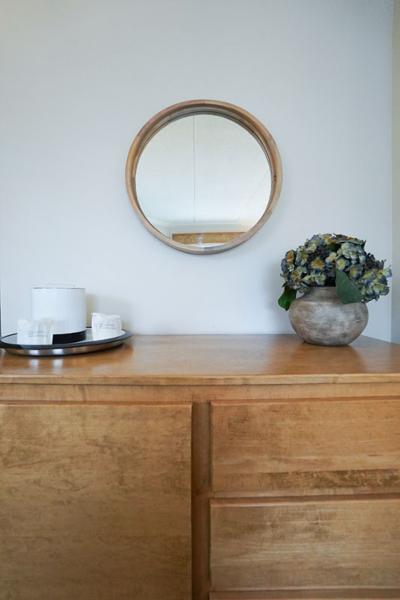 wooden dresser with a round mirror above