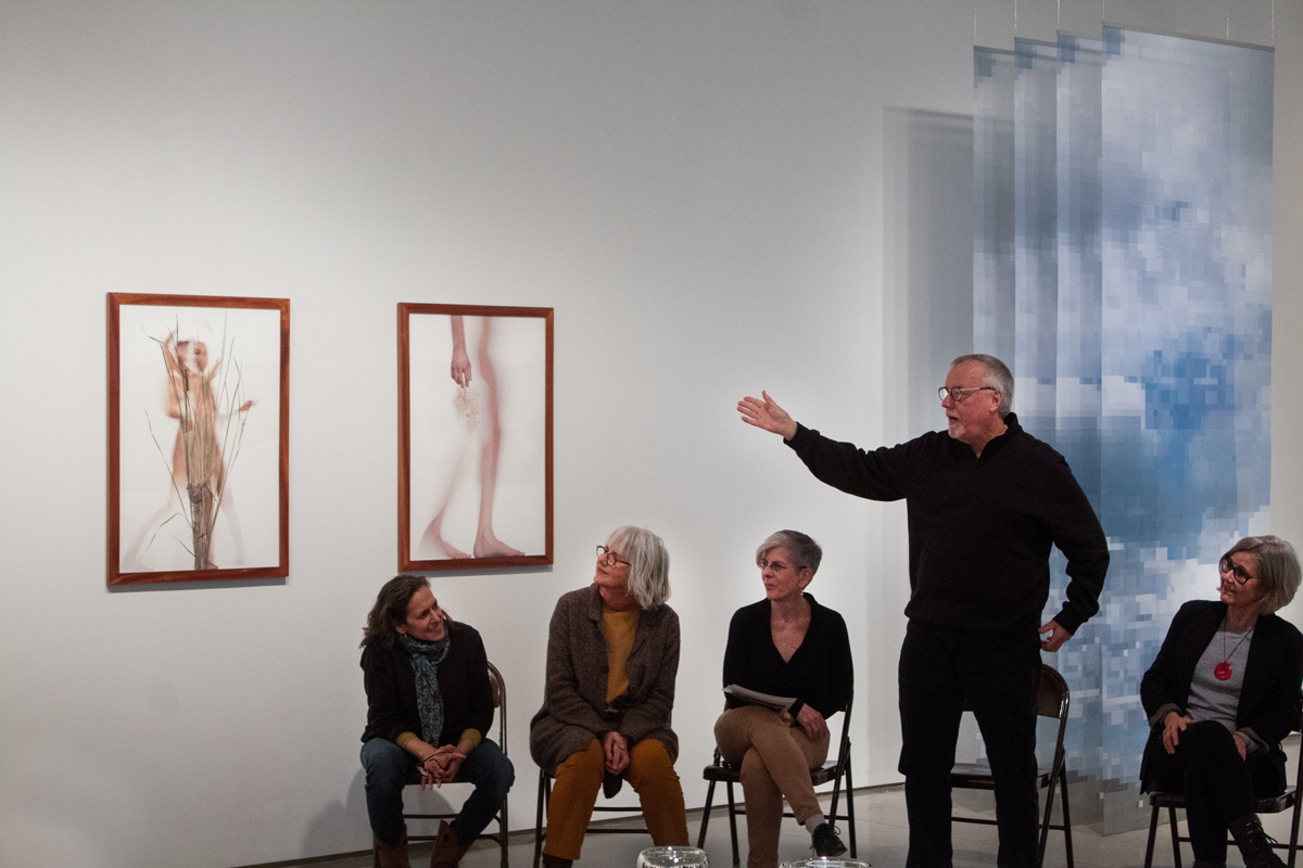 brian oglesbee talking to a group of people in the gallery space about the art featured