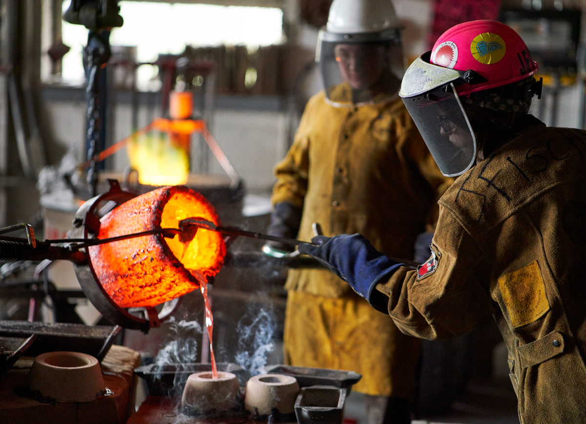 pouring molten hot metal into a mold