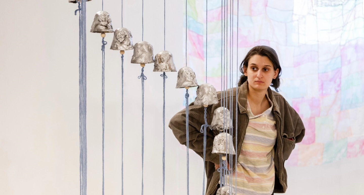person looking at a sculpture of cascading bells