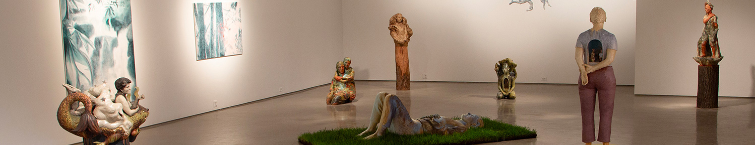 gallery space filled with various sculptures on the floor and paintings hung on the walls