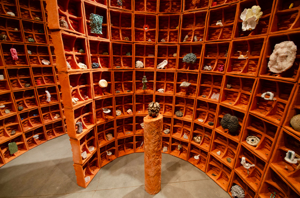 Curved wall of orange cubbies showcasing rocks, fossils, and minerals—an eye-catching display of natural history.