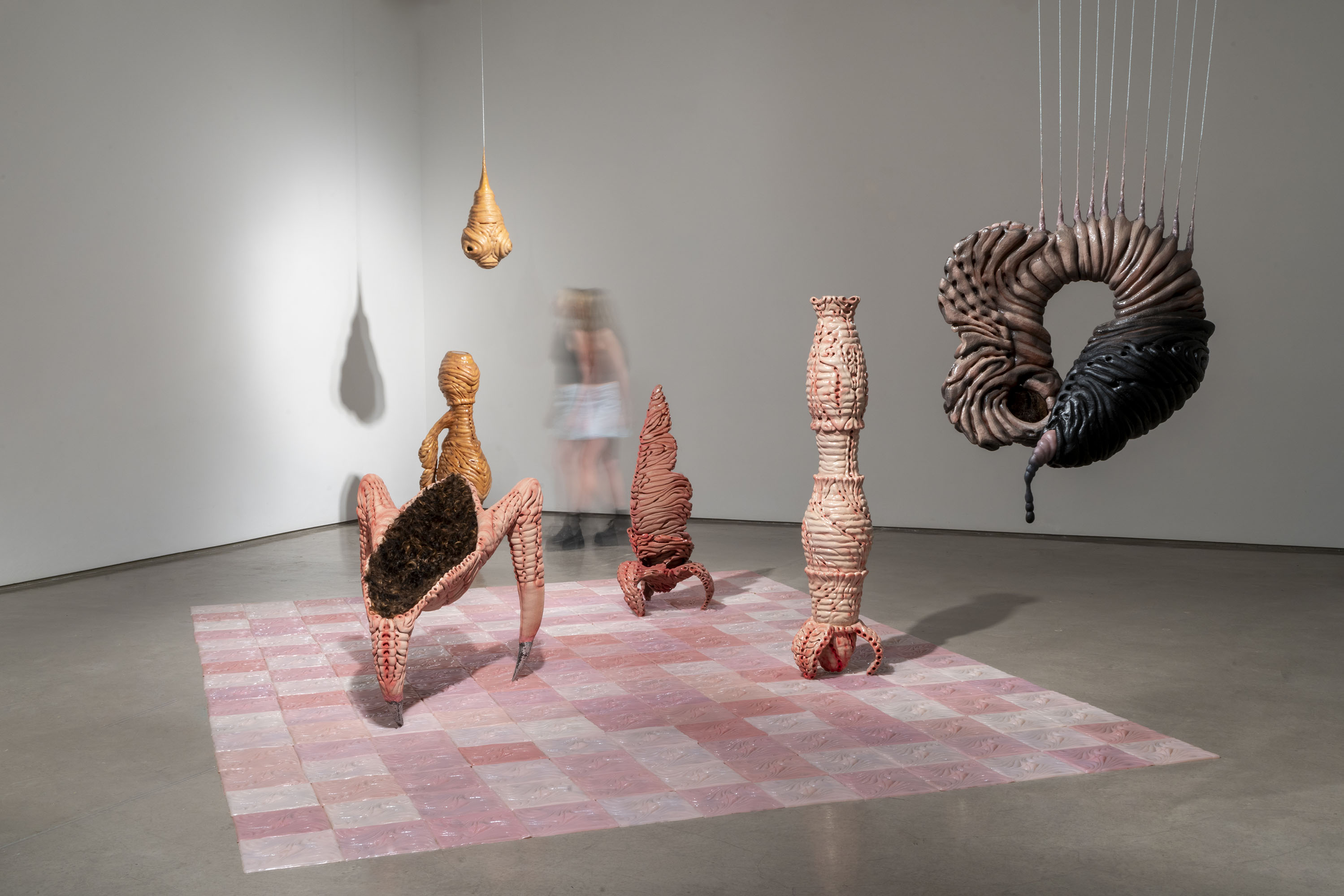 Organic-shaped sculptures hanging and standing in a gallery.