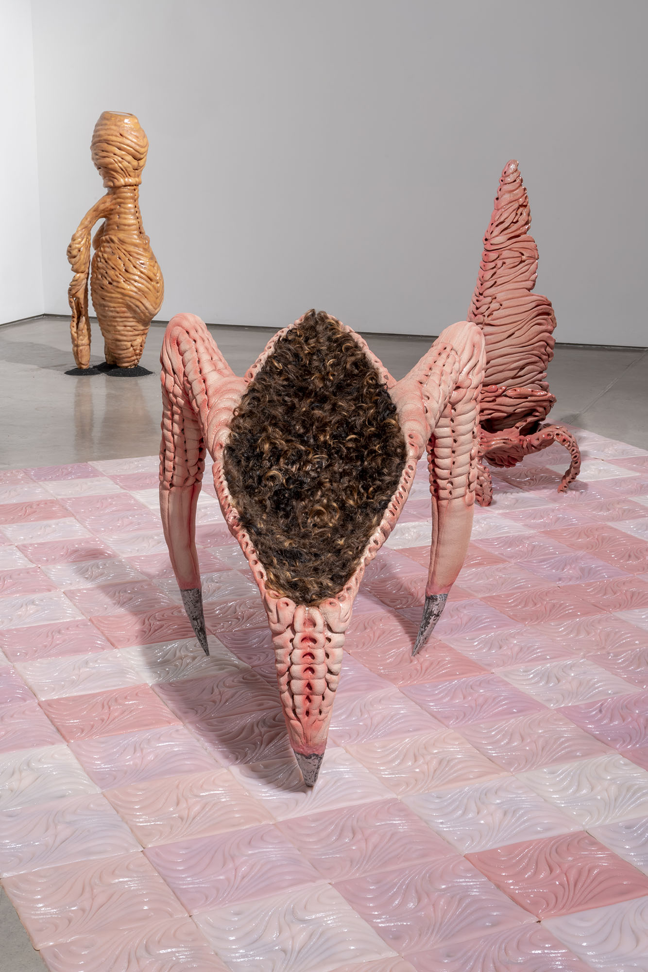 Organic-shaped sculptures hanging and standing in a gallery.