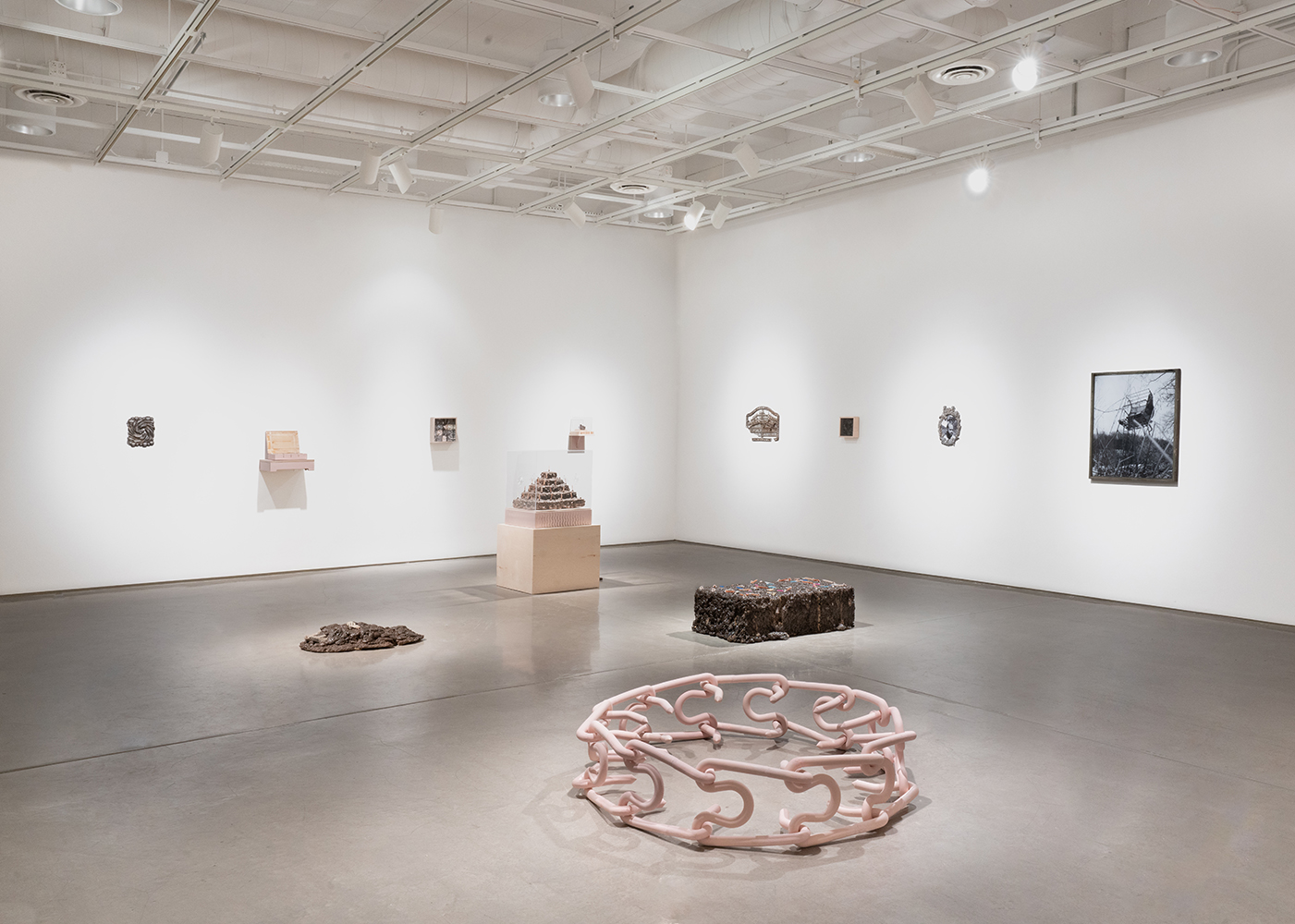 Exhibition space with statues and tables displaying artifacts under warm lighting.