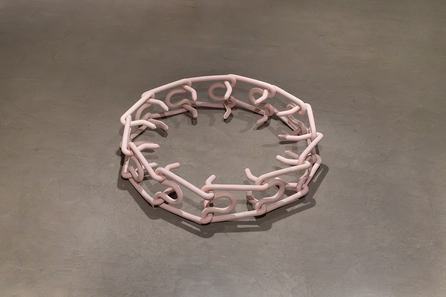 Pink chain-like sculpture arranged in a circle on the floor.