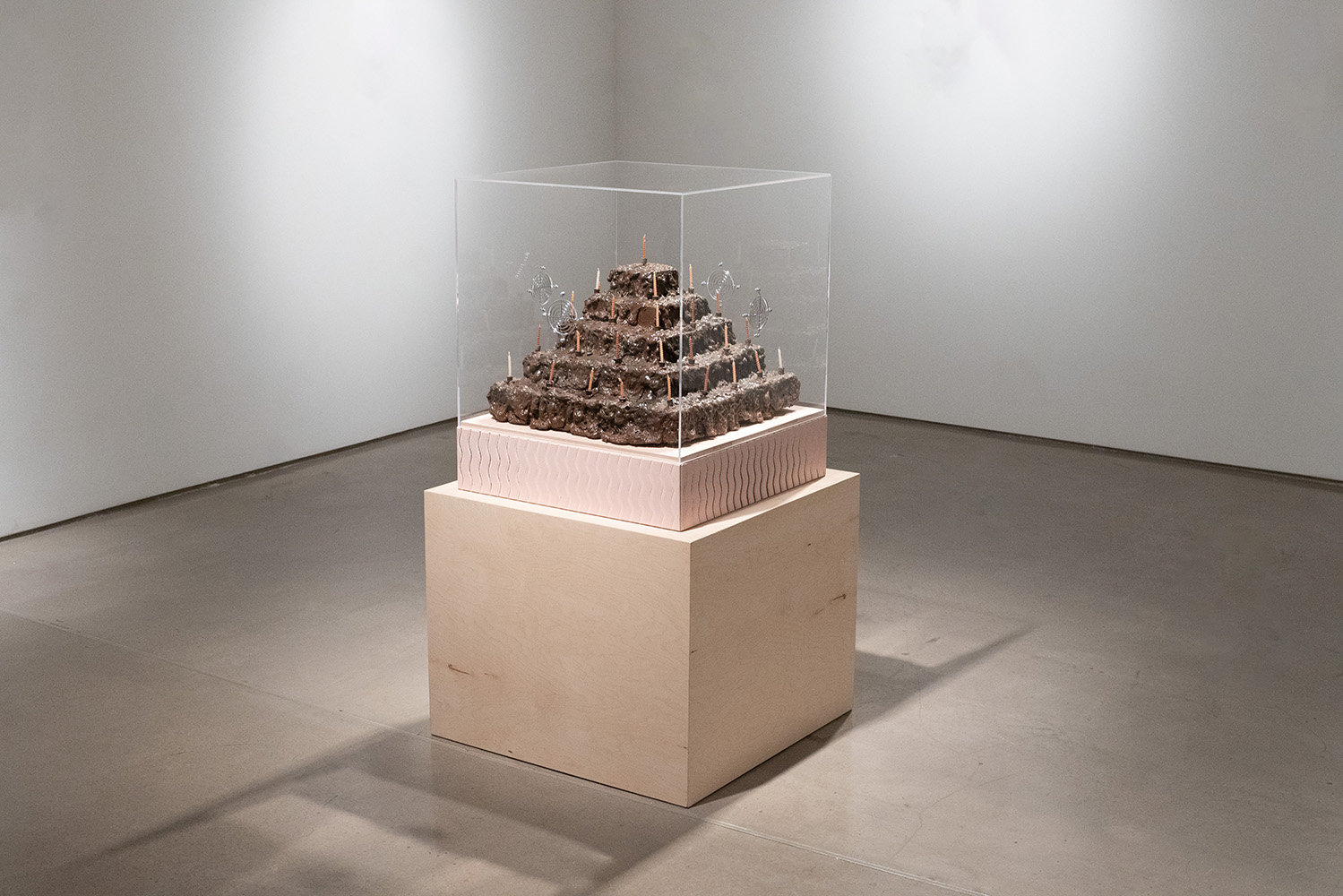 Glass-encased pyramid structure on a pedestal in a gallery.