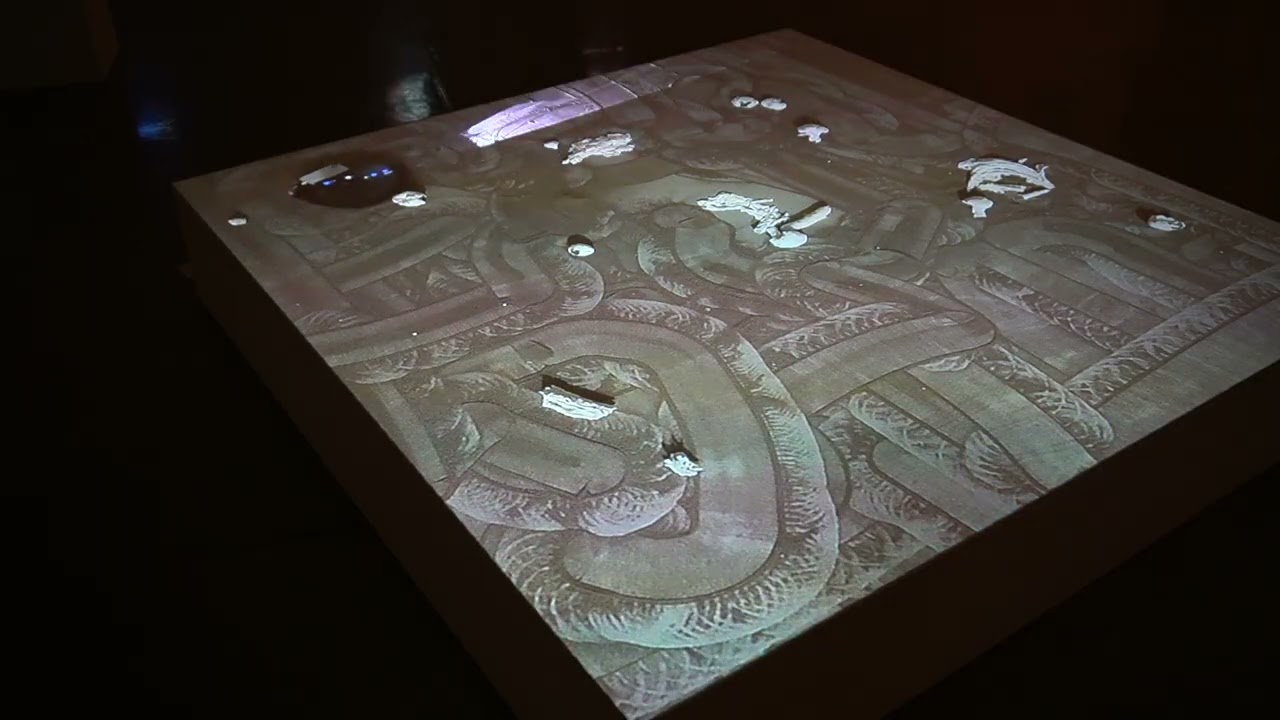 Square table displaying a projected maze-like pattern with illuminated objects scattered across its surface.