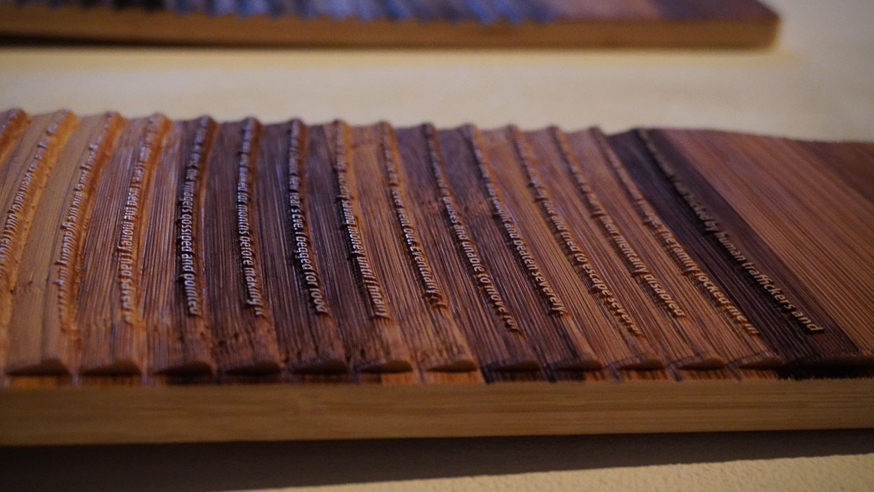 Close-up of a grooved wooden object with engraved text in each groove.