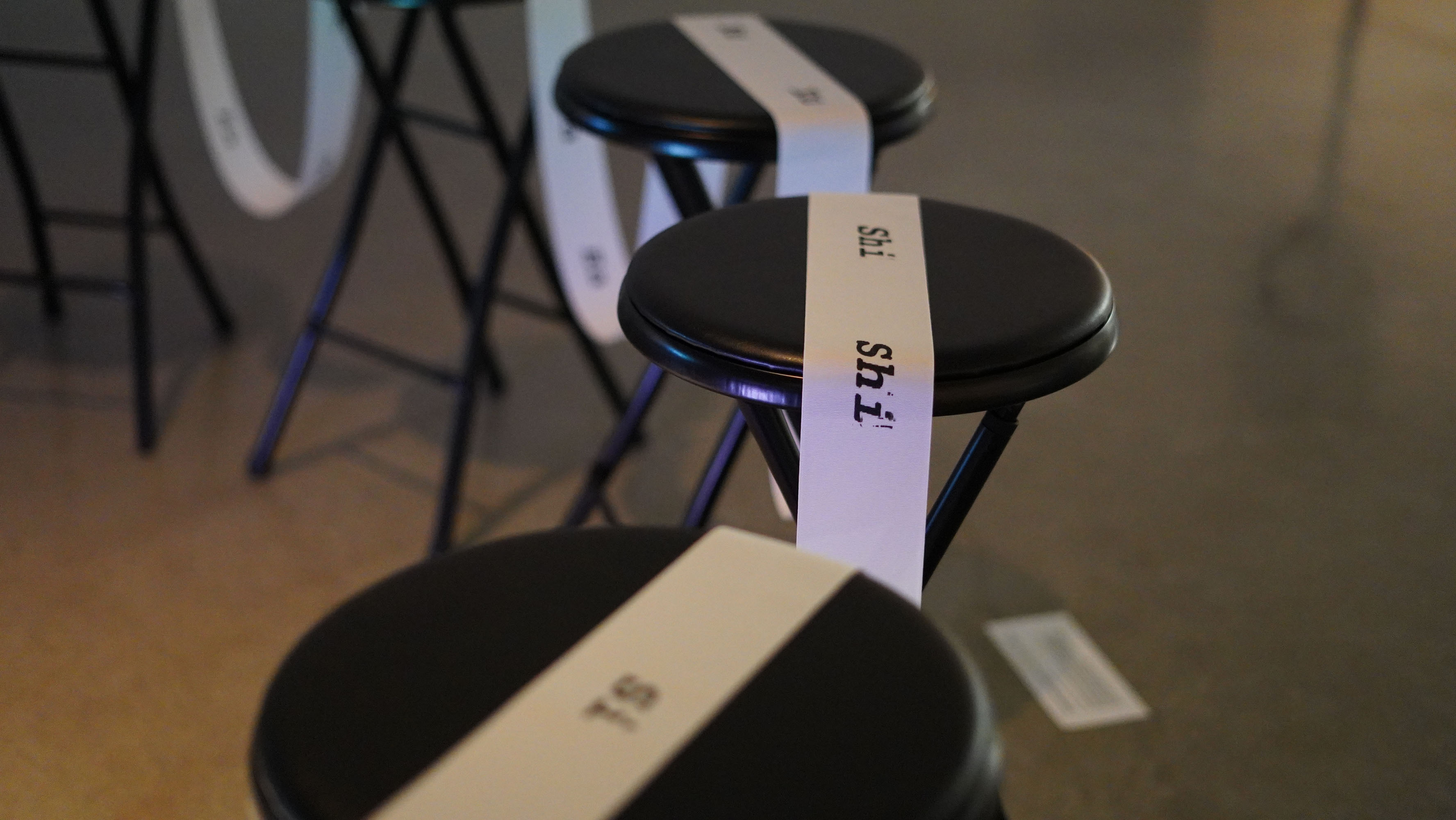 Three black stools with white ribbons labeled 'shi.'