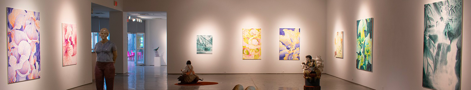 gallery space filled with paintings on the walls and sculptures on the floor