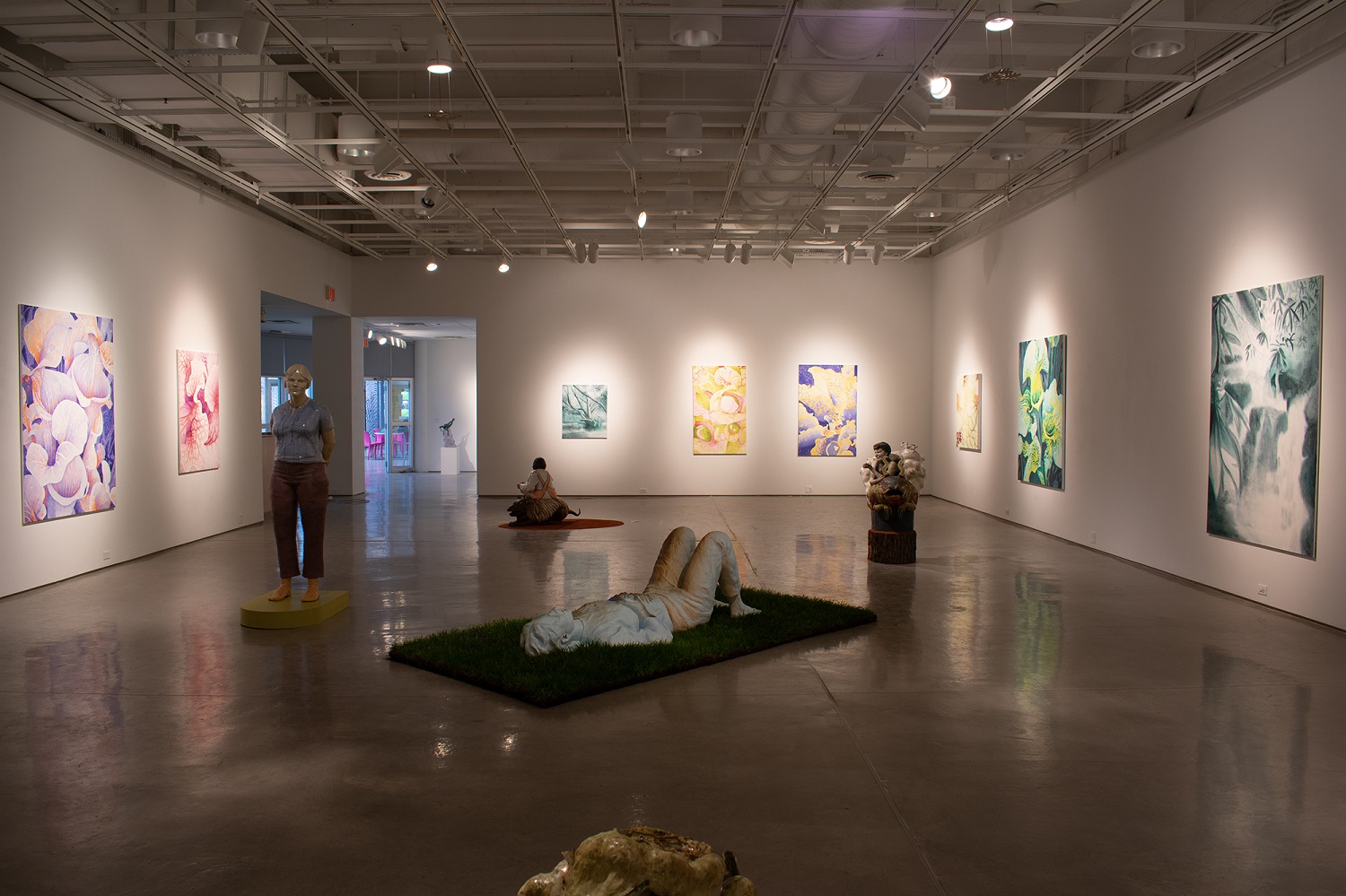 Gallery interior with colorful paintings and sculptures on display.